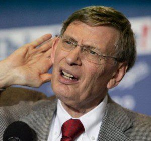 Bud Selig holds his hand to his ear to hear a question.