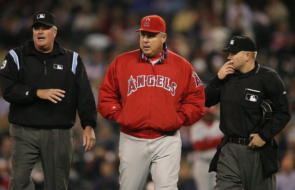 Mike Scioscia walks and talks with two umpires.