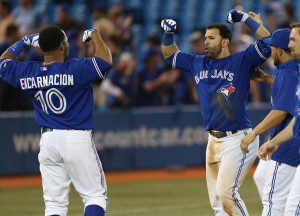 Jose Bautista celebrates a home run at home plate with teammates.
