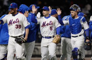 Several New York Mets players high fiving after a win.