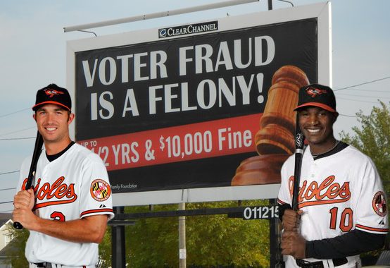JJ Hardy and Adam Jones stand in front of a voter fraud billboard.
