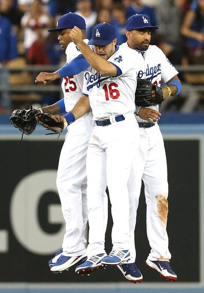 Dodgers outfielders jump up to celebrate after a win.